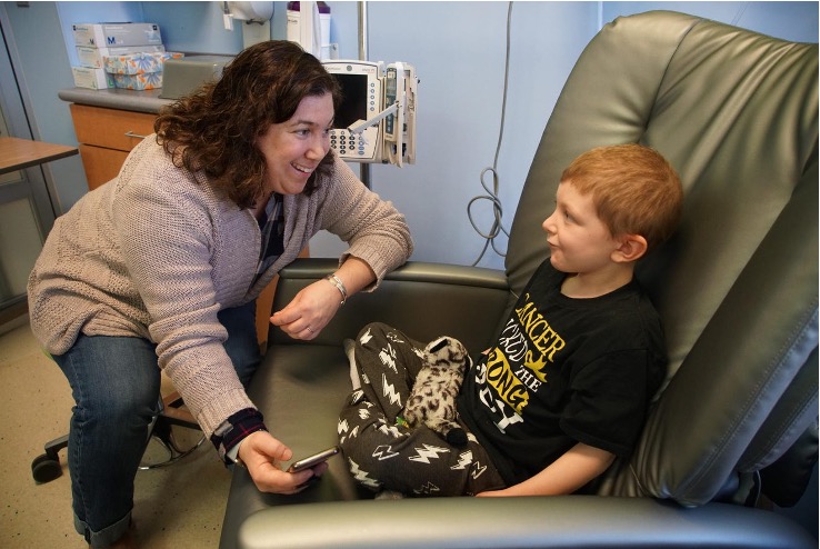 Caregiver talking with a child seated in a pediatric treatment room